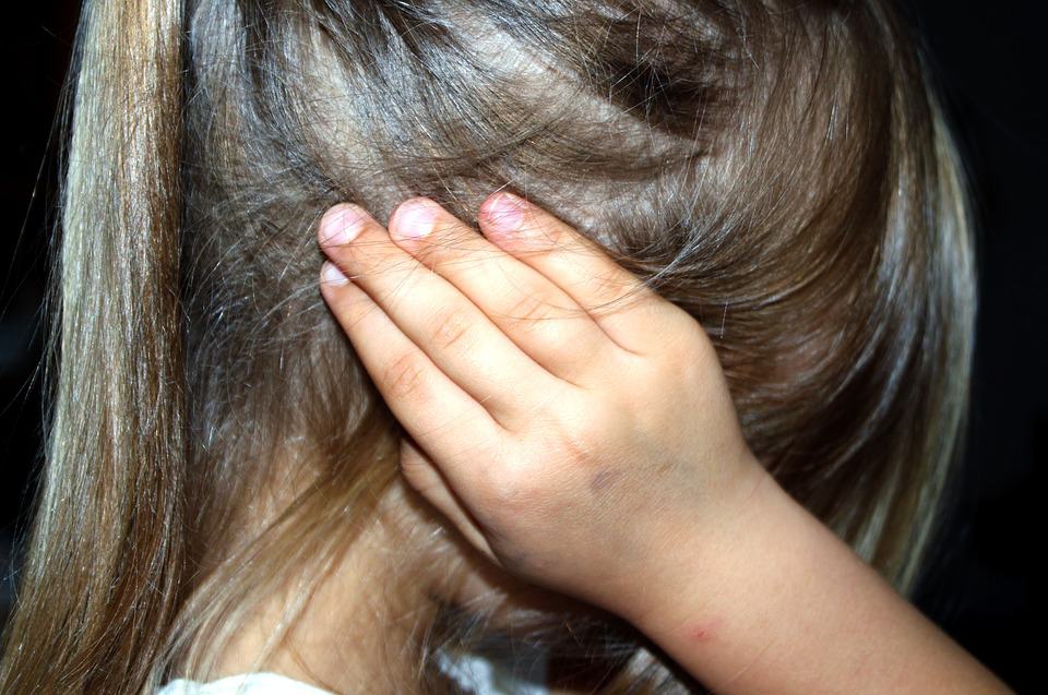 A child covers her ears in frustration over custody.