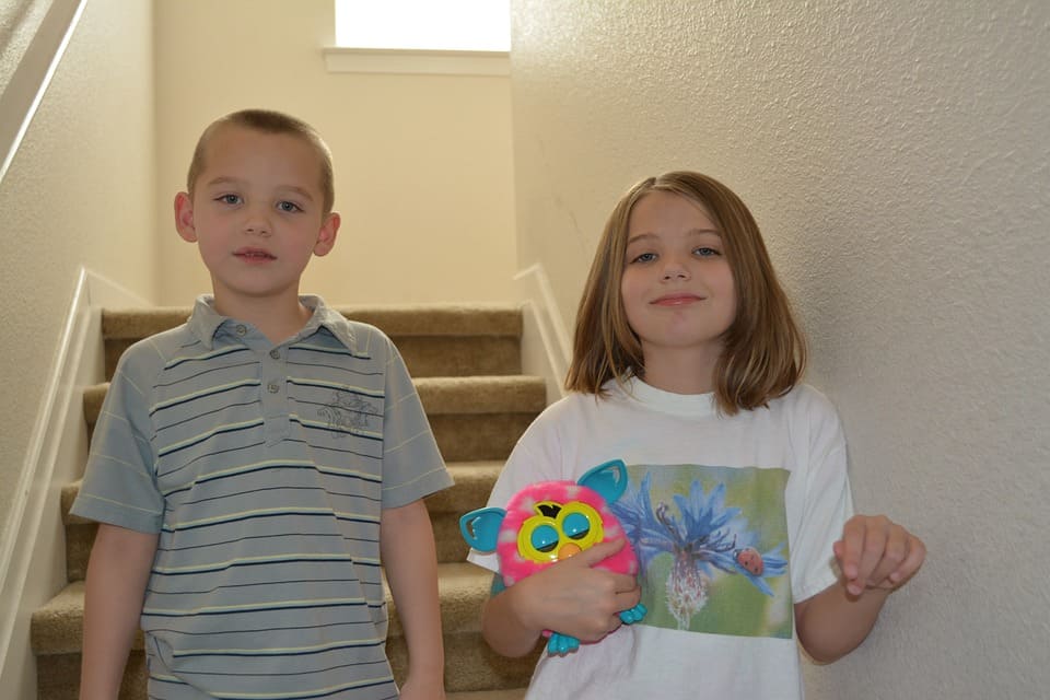 Two siblings stand on the stairs.