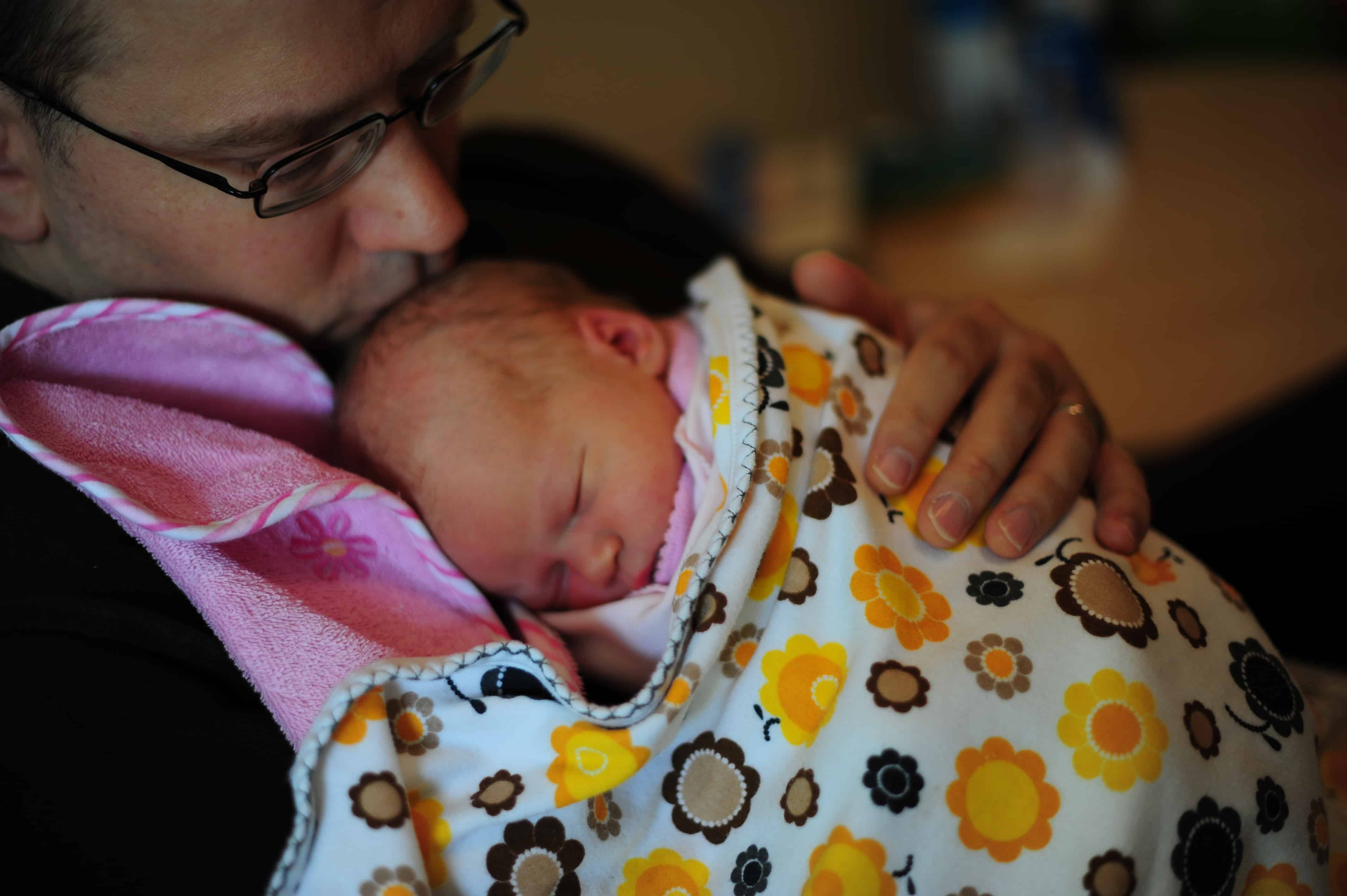 A father holds his young child in his arms.